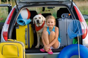 Chien et petite fille dan,s un coffre avec des bagages