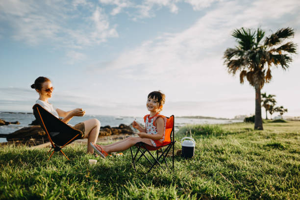 Une femme et sa petite fille assises sur des chaises de camp en pleine nature